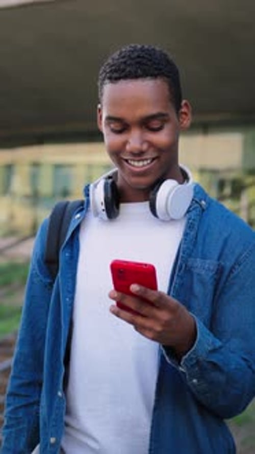 Ralenti vertical, étudiant afro-américain de sexe masculin s'amusant avec une publication sur un téléphone portable sur le réseau social