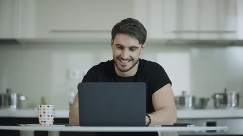 Man Works On Laptop While Drinking Coffee At Home