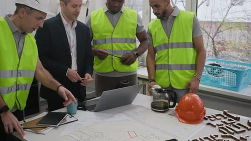 Foreman and Construction Workers Analyzing Blueprints in Office