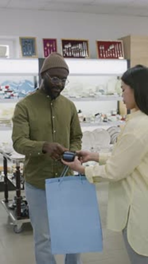 Black Man Paying with Card at Kitchenware Store and Thanking Saleswoman