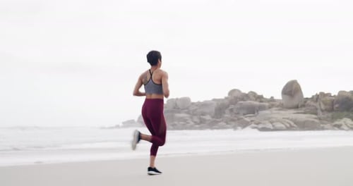 4k video footage of an attractive young sportswoman running on the beach