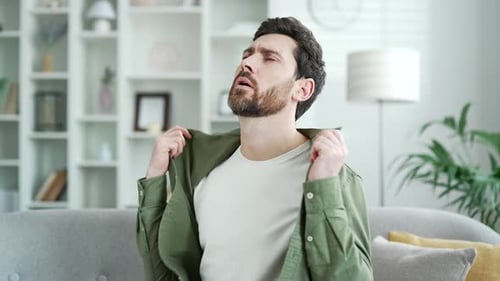 Man Fanning Himself Because of Heat Indoors