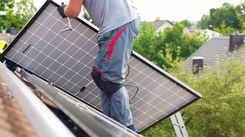 Unrecognizable Roofer carrying Solar Panel to install on top of roof, day