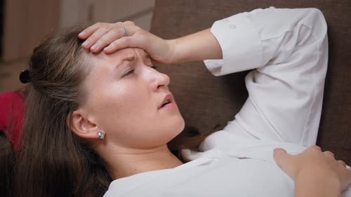 Woman Suffering From a Headache While Laying Down
