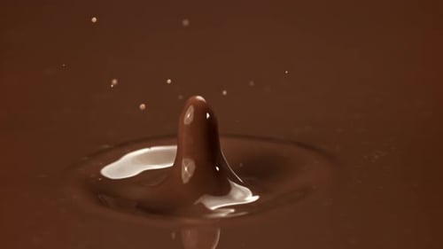 Chocolate liquid drops into molten chocolate close-up shot