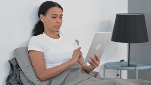 Woman Relaxes in Bed Using Tablet Technology