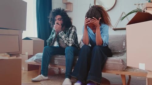 Tired Multiethnic Family Sits on Sofa After Relocation in Appartment with Boxes
