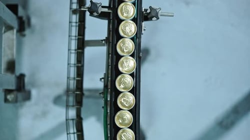 Golden topped cans running through a conveyor belt in a factory