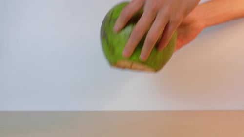 Person leaving a green coconut with a straw on the table ready to drink. Typical Southeast Asian tro