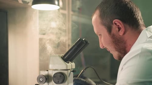 Scientist Examining Sample Under Microscope in Laboratory