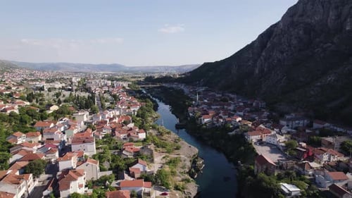 Aerial: Mostar, river winding through, framed by mountains
