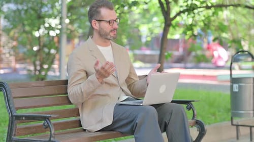 Man on Park Bench Video Calling on Laptop