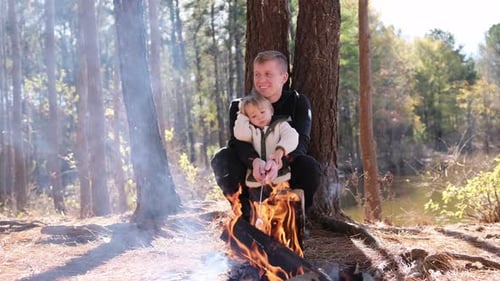 Father and Son Roasting Marshmallows on Campfire