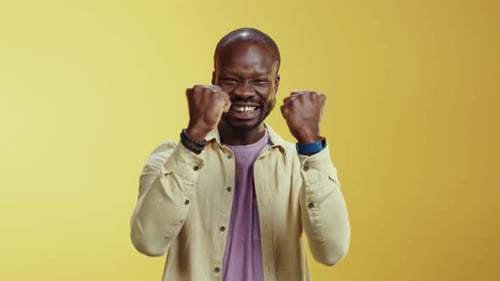 Man Cheering, Celebrating a Victory on Yellow Backdrop