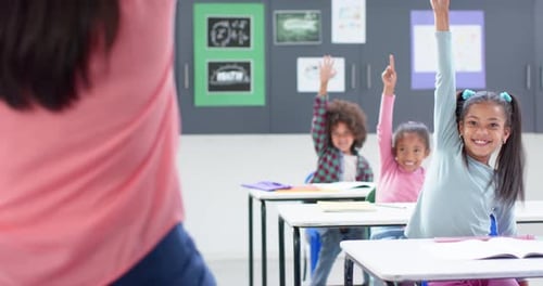 In school classroom, raising hands and smiling, students participating in lesson