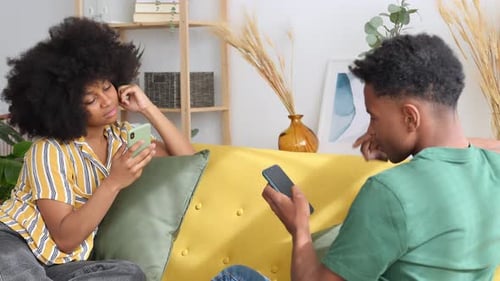 Young Couple Using Phones on Couch at Home