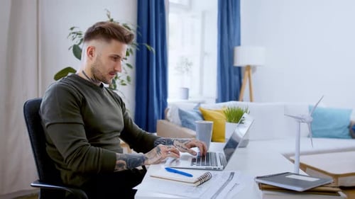 Man working on laptop at desk in living room