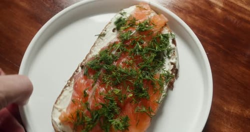Blick von oben auf ein Sandwich mit rotem Fisch Der Koch dreht den Teller in der Kamera, auf dem ein Lachs liegt