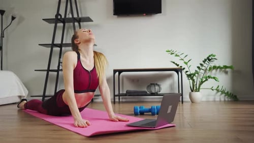 Stretching, Online-Kurs, Fitness, junge, schlanke Frau, Video auf Laptop ansehen, Training auf der Matte durchführen