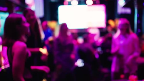 Blurred people dancing inside nightclub with dynamic lighting