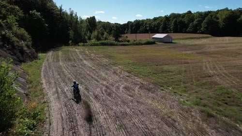 Aerial drone following enduro motocross rider in a field