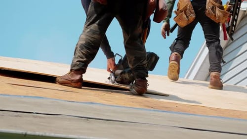 Roofer is Sawing Wooden Panels on the Residential House Element of Roof Renovation