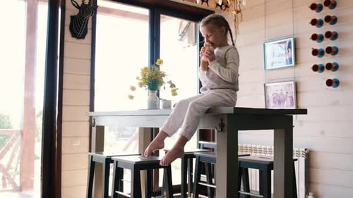 Young Girl Eating Snack on Kitchen Island
