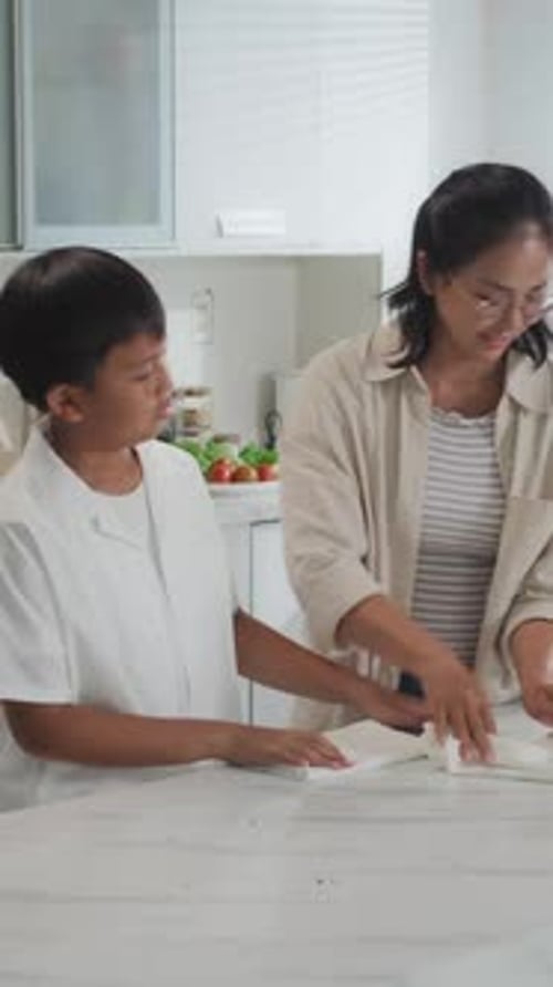 Mom Guiding Son Cleaning Kitchen Counter