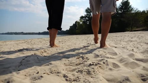 Bare Feet of Couple Stepping Together Along Beach at Ocean Background Male and Female Legs of Pair