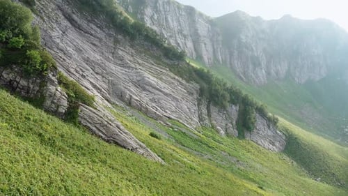 Steep Cliffs Covered with Lush Grass and Bushes in Valley