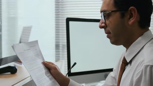 Close-up of Male Bank Employee Reading Paperwork in Office