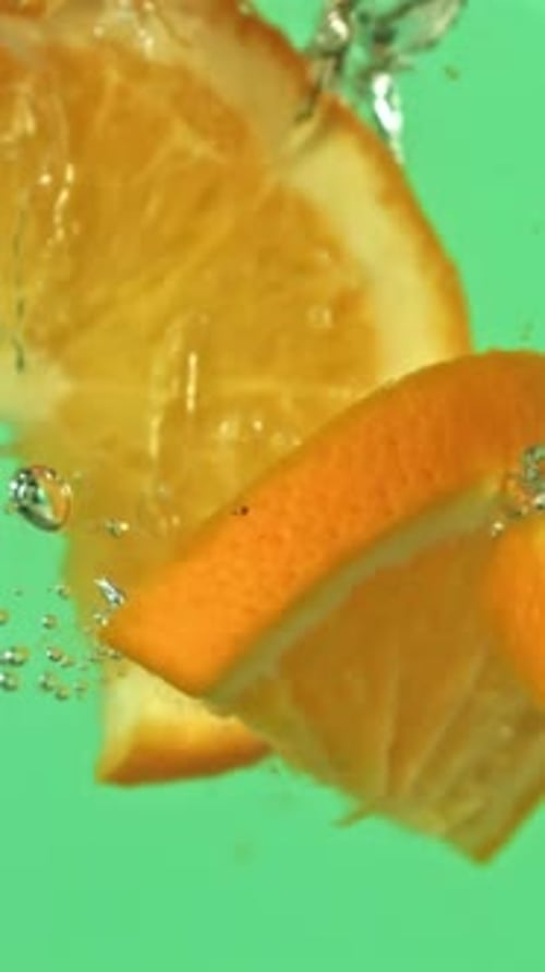 Orange Slices Falling Under Water on a Green Background Filmed on a Highspeed Camera at 1000 Fps