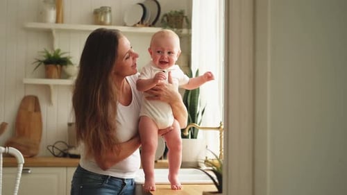 Mother Comforting Crying Baby in Bright Kitchen