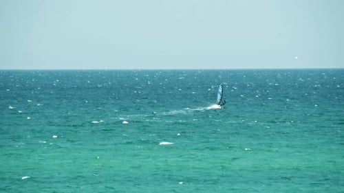 Windsurfer Riding Waves on Turquoise Ocean