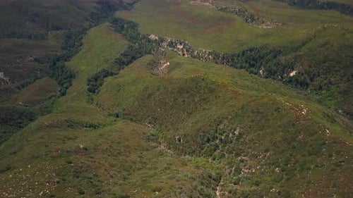 Aerial of grassy ridge and tilt up to reveal vast valley far below.
