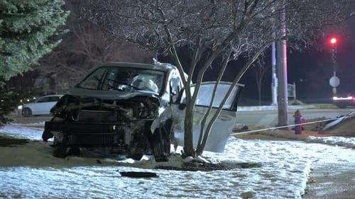 POV Close Up Nighttime Scene of a Damaged Car After a Crash Resting on a Snowy Roadside Traffic