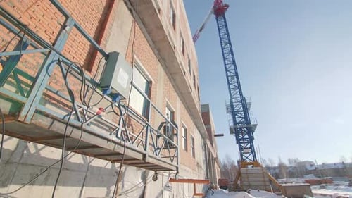 Cuna y grúa de torre alta cerca del edificio de la antigua fábrica