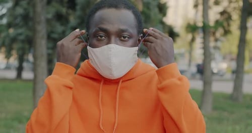 Young Adult Putting On a White Mask