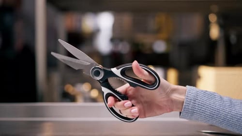 Closeup in a Professional Kitchen Girl's Hand is Testing New Scissors for Cutting Chicken