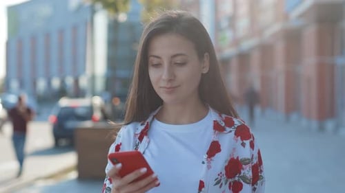 Attractive Caucasian Girl Holding Looking on Smartphone Screen Standing in the Street Outdoor