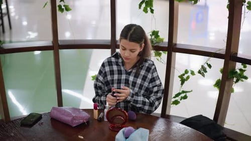 Young Woman Applies Makeup at Table