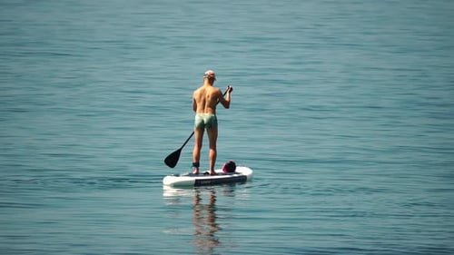 Sea Man Sup Athlete Man Floating in Calm Sea and Paddleboarding at Summer Sunset Healthy Strong Male