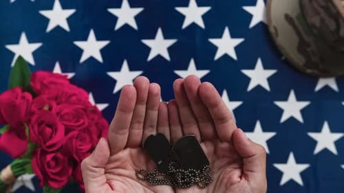 Hands Holding Dog Tags over US Flag with Roses