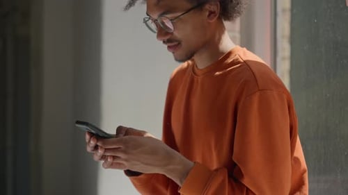 African American Male Student Chatting on Mobile Phone in University Corridor Guy Man Schoolboy