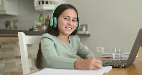 Female kid doing online private school class using laptop for video call at home - Education