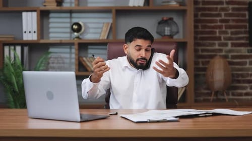 Young Adult Using Laptop and Phone at Desk