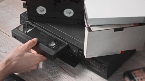 Male Hand Inserts VHS Cassette Into a VCR Video Recorder