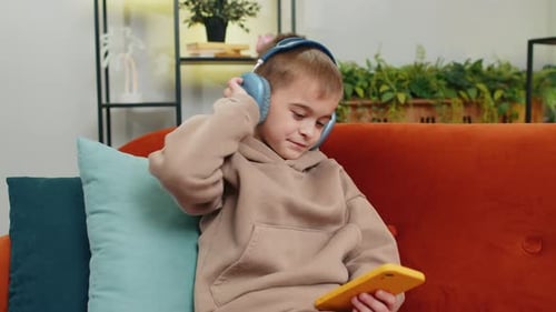 Boy Listening to Music on Smartphone with Headphones Indoors