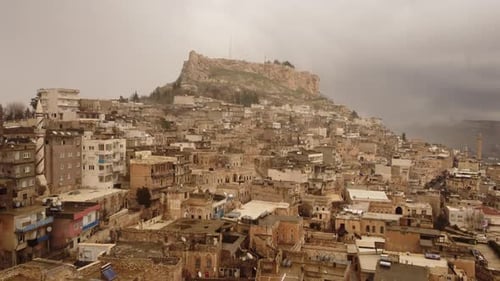 Paysage urbain à flanc de colline avec des bâtiments en pierre denses sous un sommet rocheux à Mardin en Turquie