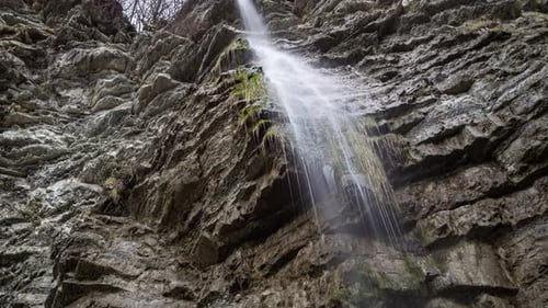 Panoramic view of a small waterfall on a large rock